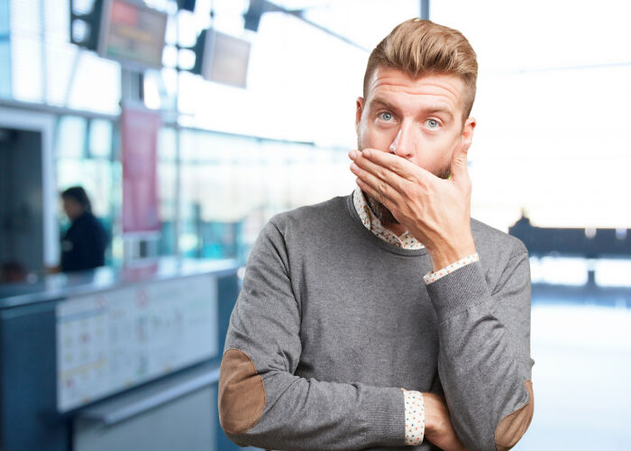 Young man covering his mouth with hand looking surprised, illustrating moments when folks accidentally hurt loved ones with funny words.
