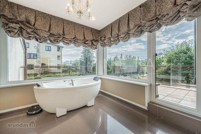 Modern bathroom with a freestanding tub and large corner windows in a wild real estate listing with scenic views.