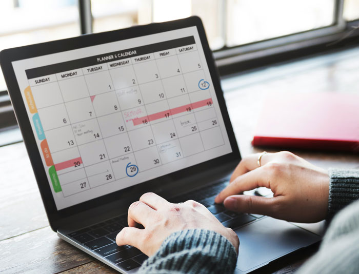 Person checking digital calendar on laptop, planning time off after finding a loophole in employee handbook rules. Person checking digital calendar on laptop, planning time off after finding a loophole in employee handbook rules.
