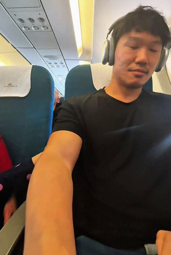 Frequent traveler wearing headphones on an airplane experiencing discomfort from a kid kicking during flight. Frequent traveler wearing headphones on an airplane experiencing discomfort from a kid kicking during flight.