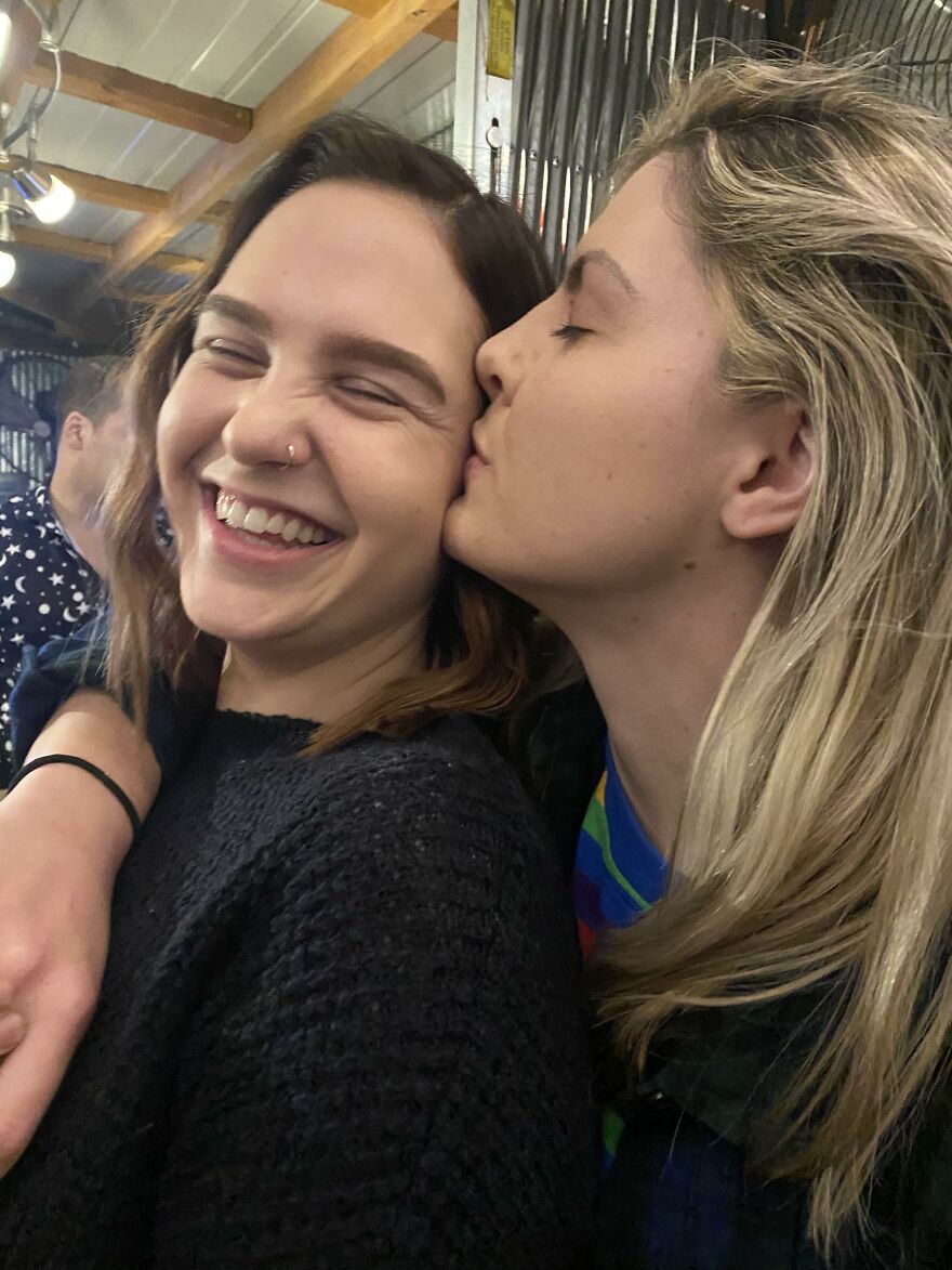Two women sharing a joyful moment with a gentle kiss, illustrating different types of kisses and their cultural meaning.