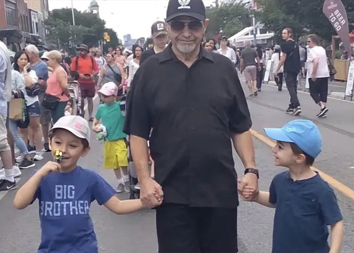 Man in black shirt and cap holding hands with two young boys in crowded outdoor street scene, broken mother story context. Man in black shirt and cap holding hands with two young boys in crowded outdoor street scene, broken mother story context.