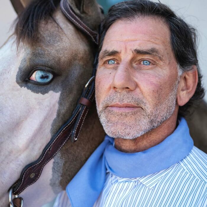 Man and his horse standing close with strikingly similar blue eyes, showing pets and their humans look alike.