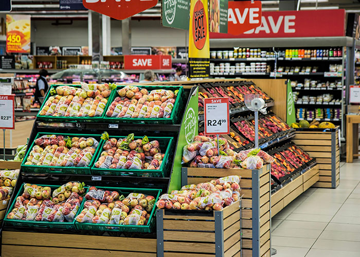 Produce section of a grocery store with fresh fruits and shoppers exploring useful life hacks for better shopping experiences.
