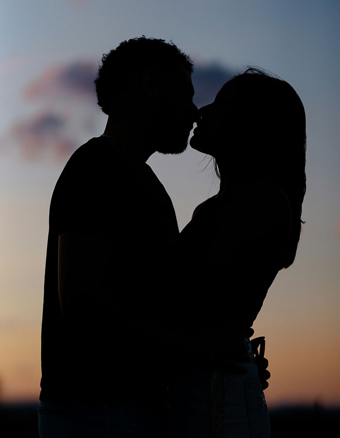 Silhouette of a trainee police officer and her boyfriend sharing a close moment at sunset, hinting at secretive relationship.
