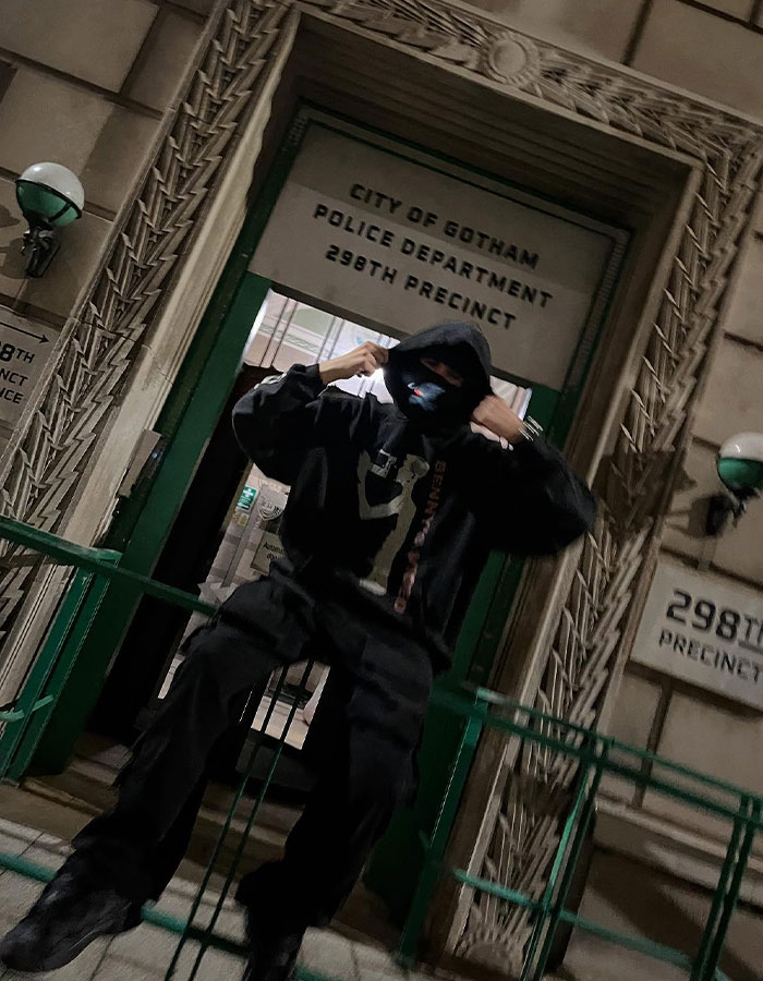 Person in dark hoodie and mask posing outside the City of Gotham Police Department, linked to Timothée Chalamet EsDeeKid theory. Person in dark hoodie and mask posing outside the City of Gotham Police Department, linked to Timothée Chalamet EsDeeKid theory.