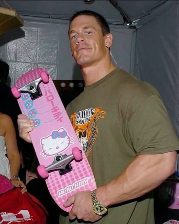Man holding a pink Hello Kitty skateboard, showcasing popular pics that go hard with a confident expression indoors.