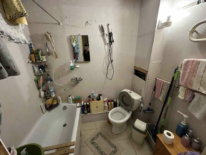 Small cluttered bathroom with toilet and bathtub, featured in wild real estate listings attempting to help sell properties.