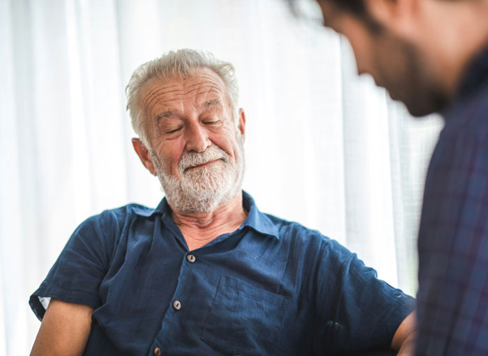 Elderly man in blue shirt interacting with younger person, conveying entitled parents ignoring autistic brother’s behavior.