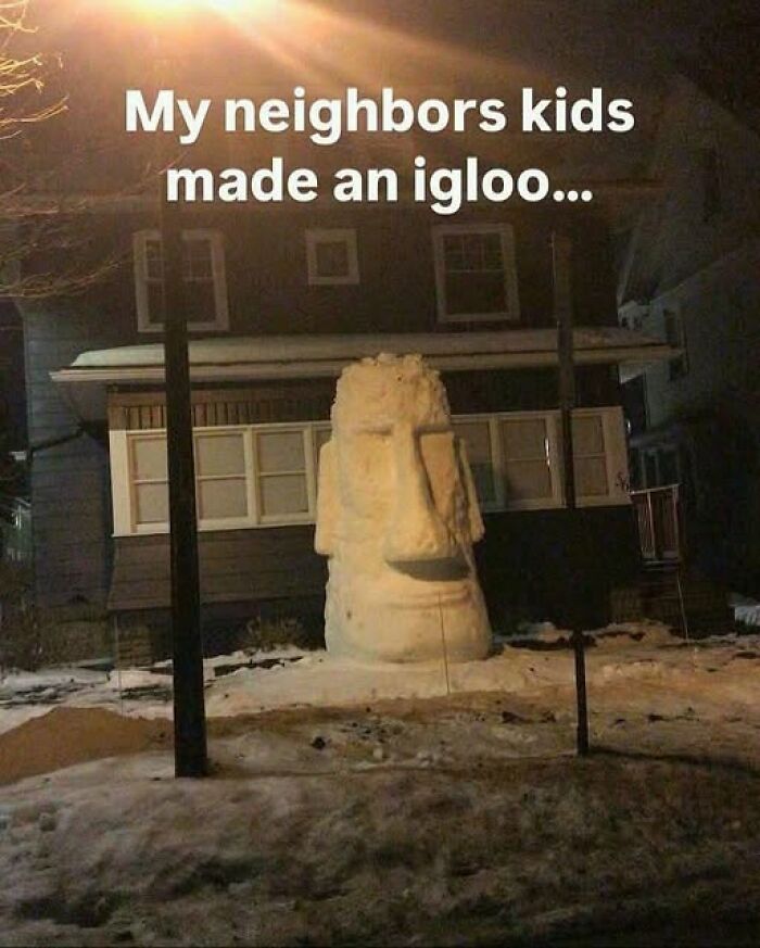 Large snow sculpture resembling a Moai head in a yard at night, featured among pics that go hard and are popular online.