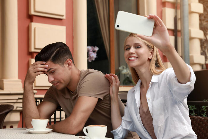 A woman takes a selfie smiling while a man looks stressed, illustrating stories of people who messed up once and learned.