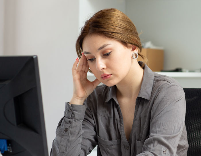 Woman at office desk looking stressed, reflecting the impact of eating what she shouldn't on a coworker. Woman at office desk looking stressed, reflecting the impact of eating what she shouldn't on a coworker.