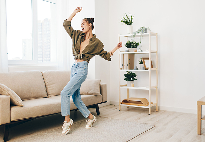 Young woman sharing inspiring update dancing joyfully in bright living room after leaving cheating husband.