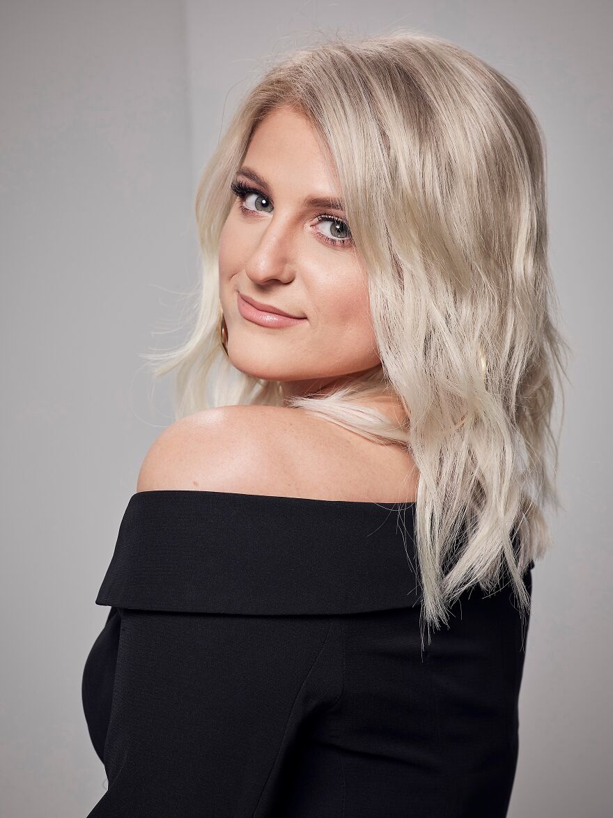 Meghan Trainor posing in a black off-shoulder top, showcasing her transformation in before and after photos. Meghan Trainor posing in a black off-shoulder top, showcasing her transformation in before and after photos.