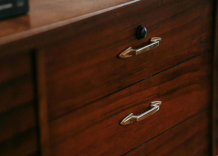 Close-up of wooden cabinet drawers with metal handles, illustrating genius cleaning hacks inspired by laziness.