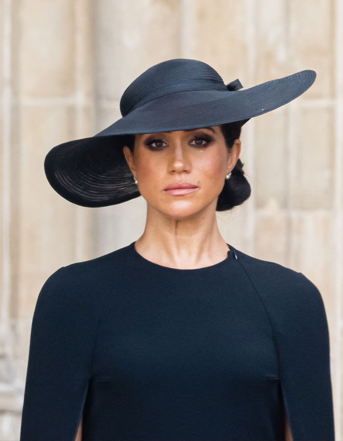 Meghan Markle in a black wide-brim hat and dress, capturing a striking Harper’s Bazaar moment that sparked internet buzz.
