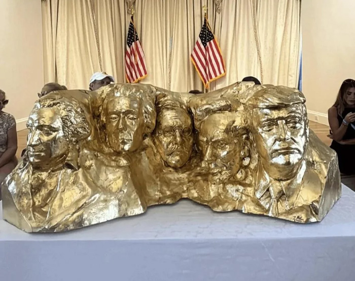 Golden sculpture of five US presidents with American flags in the background, symbolizing Kristi Noem transformation.