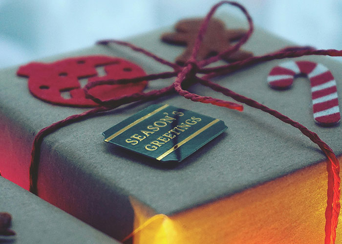 Close-up of a wrapped gift with a season's greetings tag, illustrating people sharing life hacks for easy holiday wrapping.