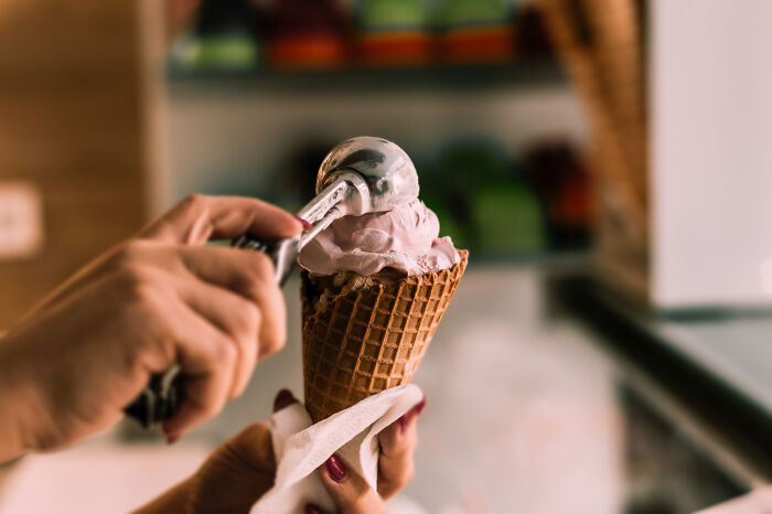 Person scooping ice cream into a waffle cone, illustrating stories of lessons learned from mistakes and never again moments. Person scooping ice cream into a waffle cone, illustrating stories of lessons learned from mistakes and never again moments.