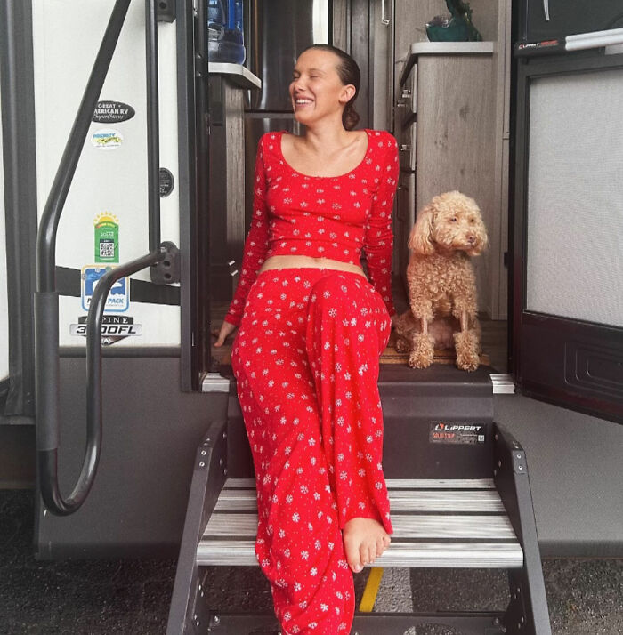 Stranger Things star in red outfit sitting on steps beside dog, exposing and denouncing bullying suffered by Millie Bobby Brown. Stranger Things star in red outfit sitting on steps beside dog, exposing and denouncing bullying suffered by Millie Bobby Brown.