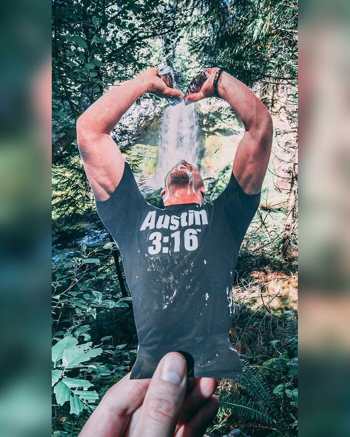 Hand holding a paper cutout of a man drinking water, aligning perfectly with a real waterfall in the forest scene.