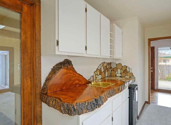 Unique Zillow homes feature a live edge wood countertop and stone backsplash in a modern kitchen setting.