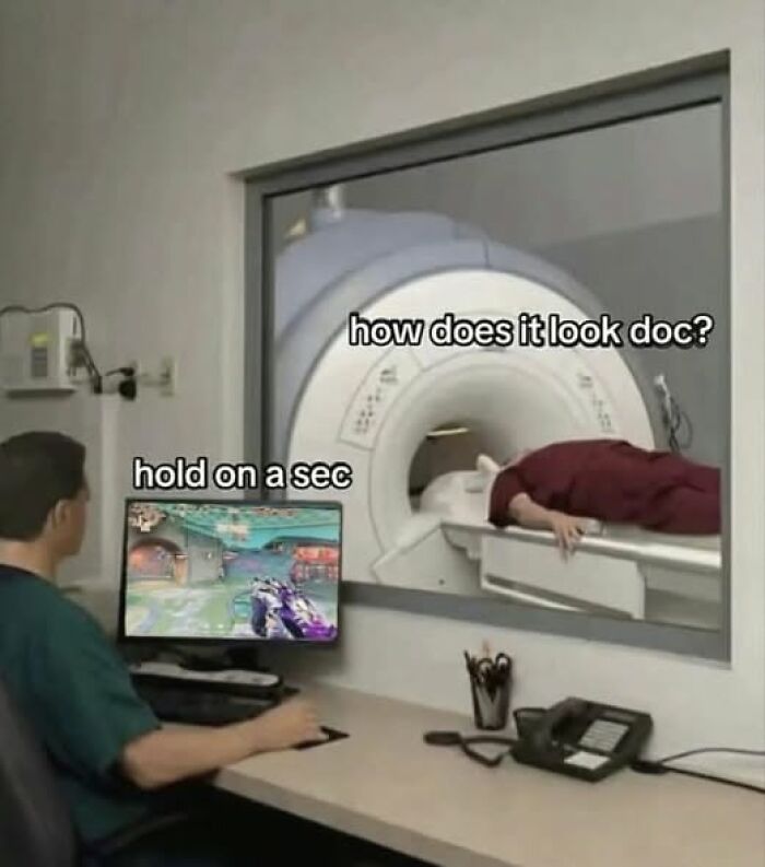 MRI technician playing video game while patient is inside MRI machine in a humorous pic that goes hard and is widely liked.
