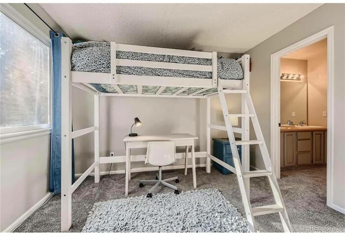 Loft bed with desk and chair in a bright Zillow home featuring neutral colors and modern minimalist design.