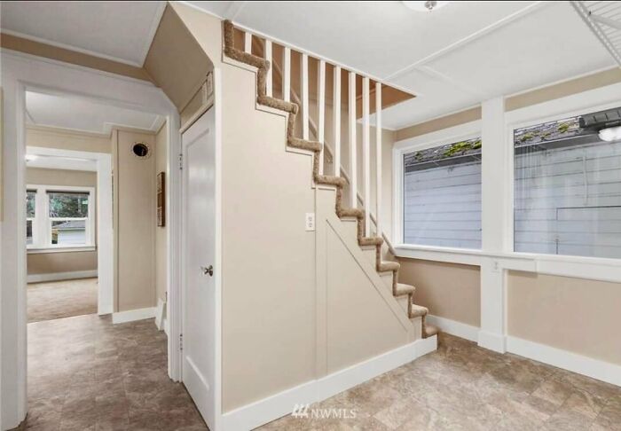 Bright interior of a Zillow home featuring carpeted stairs, large windows, and neutral-toned walls and flooring.