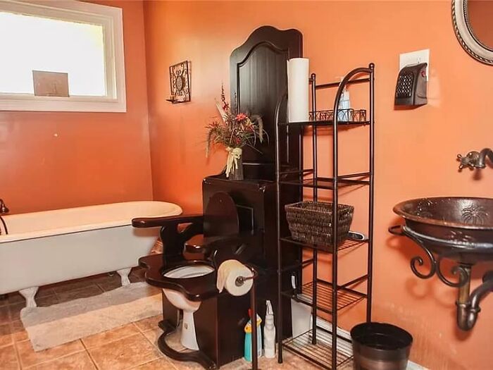 Unique Zillow homes bathroom with antique-style toilet, clawfoot tub, and rustic metal sink in warm orange decor