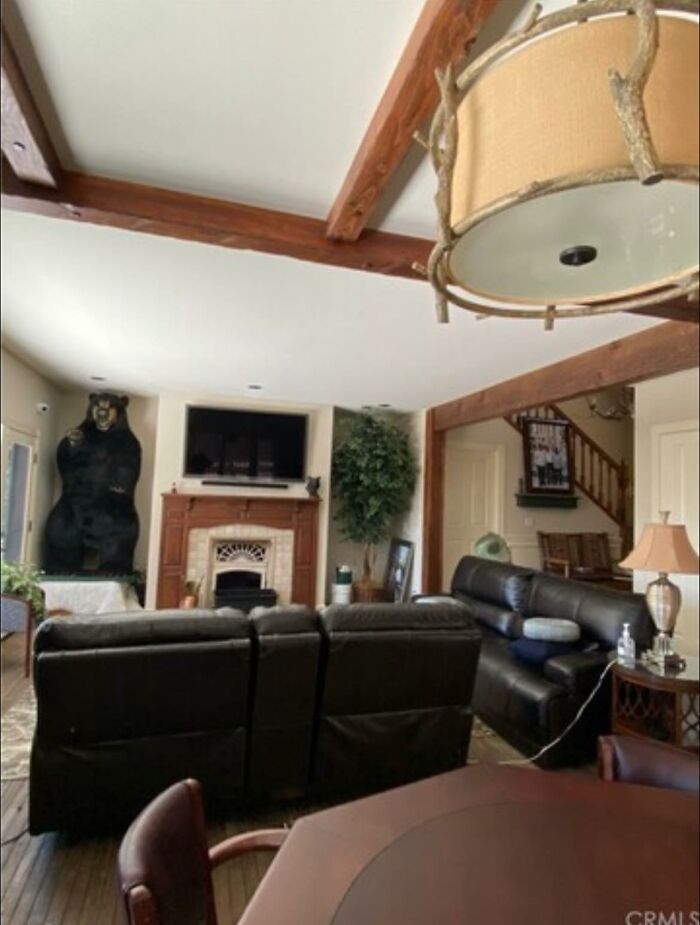 Living room with leather sofas, rustic wooden beams, and a bear statue in unique Zillow homes for sale.