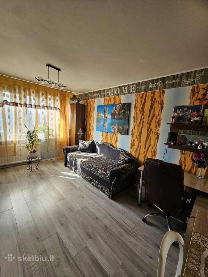 Living room with patterned sofa, bright curtains, and unique wall design in a wild real estate listing photo.