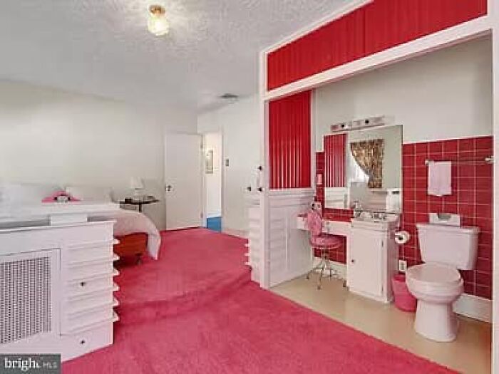 Bright bedroom with pink carpet and red tiled bathroom area, featuring unique design in Zillow homes you have to see.