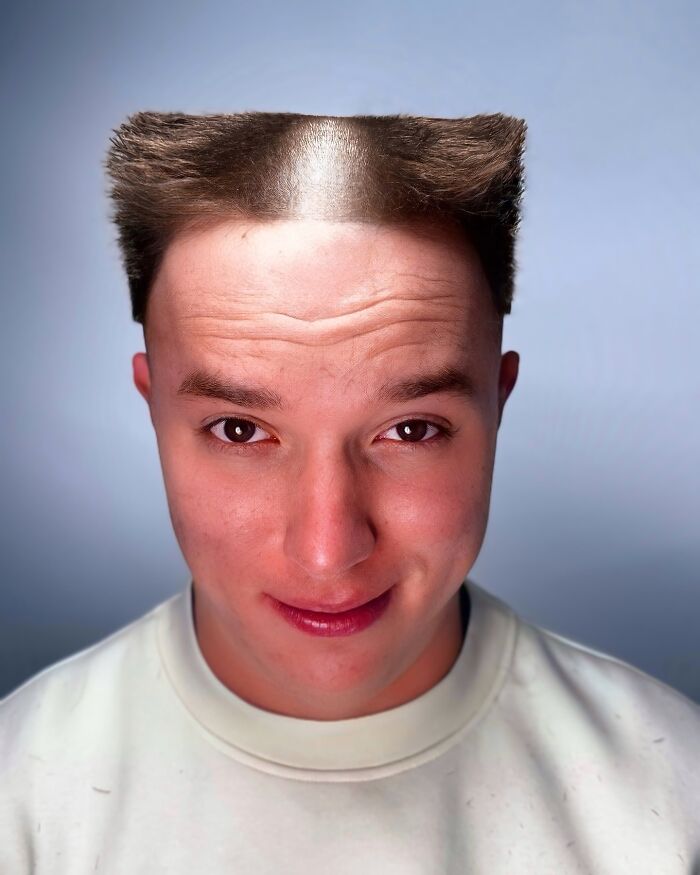 Young man with a bold barber haircut featuring sharp, flat-top styled hair on the sides and top against a plain background.
