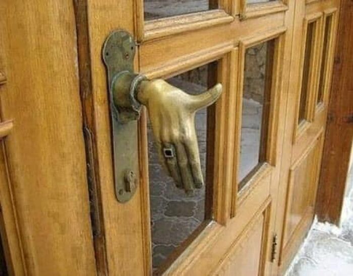 Unique door handle shaped like a hand on a wooden door, one of the Zillow homes you have to see to believe.