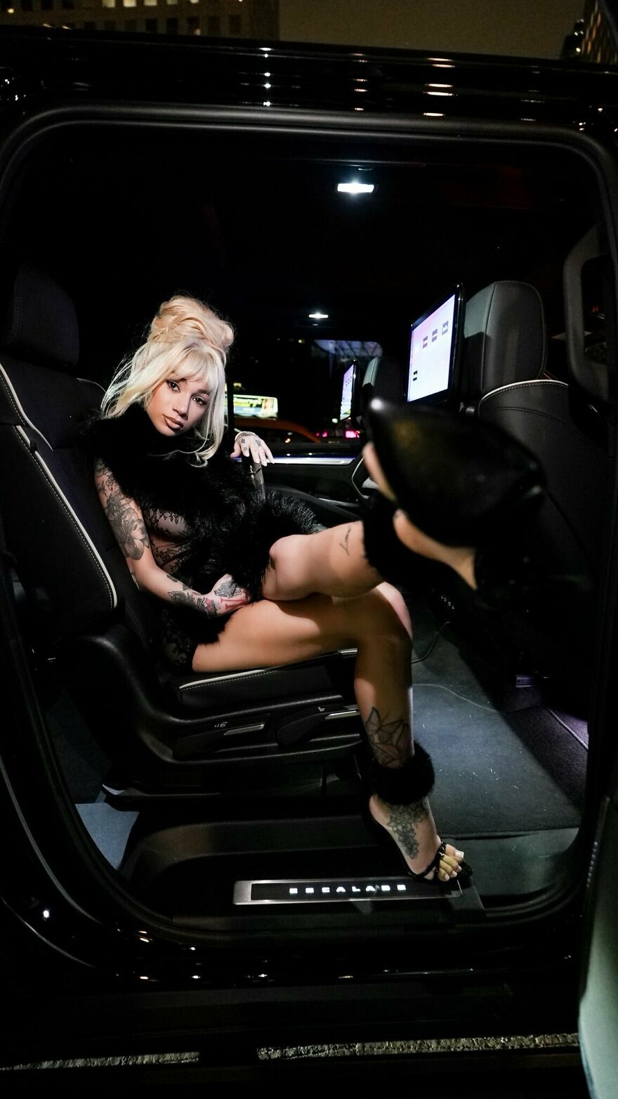 Bhad Bhabie posing confidently inside a luxury vehicle showing stylish tattoos and glamorous fashion at night. Bhad Bhabie posing confidently inside a luxury vehicle showing stylish tattoos and glamorous fashion at night.