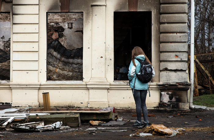 Urban explorer with backpack standing near a creepy abandoned building during a terrifying urban exploration moment.