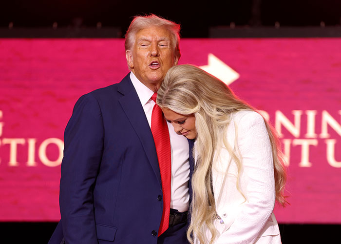 Man in suit and red tie speaking while a woman with long blonde hair leans in, gestures hint at expressive acting and emotions. Man in suit and red tie speaking while a woman with long blonde hair leans in, gestures hint at expressive acting and emotions.