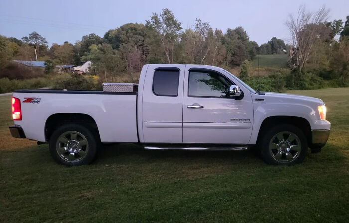 White pickup truck parked on grass near rural area, related to man leaving 2YO daughter in burning car after drunk crash.
