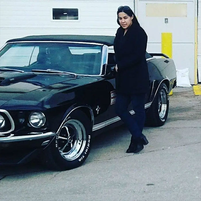 Woman in black coat standing next to a vintage black car, related to broken mother learning fate after slaying sons. Woman in black coat standing next to a vintage black car, related to broken mother learning fate after slaying sons.