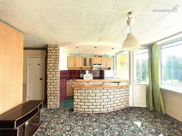 Interior view of a wild real estate listing featuring a vintage kitchen with brick accents and large windows.