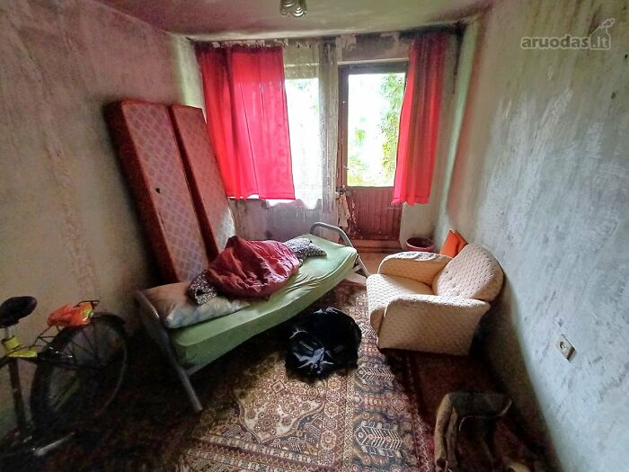 Small cluttered room with old furniture and red curtains in a wild real estate listing that people thought would help sell properties.