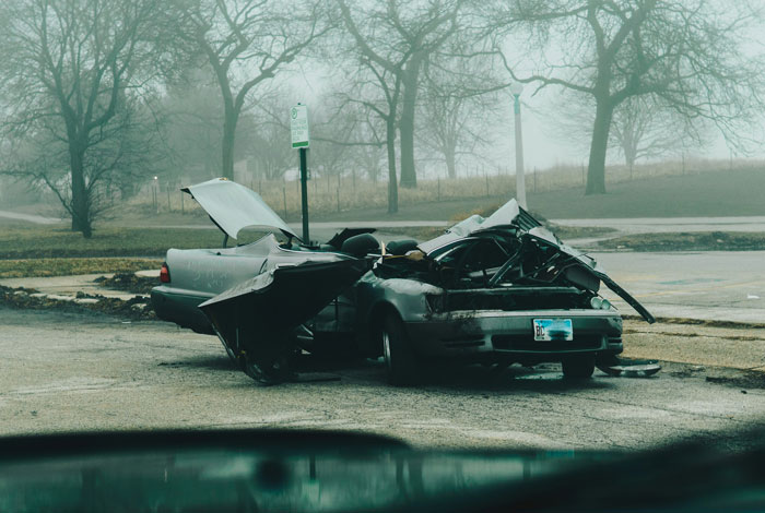 Severely damaged car in a foggy parking lot, illustrating wildest family drama shared by people online.