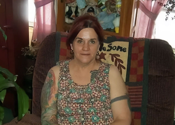 Woman with tattoos sitting on a chair indoors with plants and dolls in the background missing woman’s body discovered in garage.