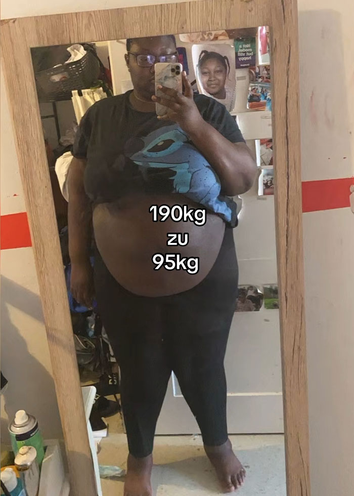 Woman taking a mirror selfie showing loose skin on belly after massive weight loss, demonstrating trick to hide it.
