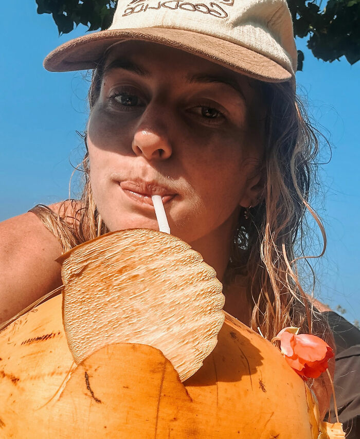 Woman revealing disturbing truth about solo traveling while sipping a drink outdoors wearing a cap under clear blue sky. Woman revealing disturbing truth about solo traveling while sipping a drink outdoors wearing a cap under clear blue sky.