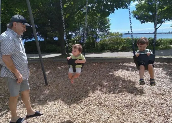 Man in cap pushing two young sons on swings at a park near water, related to broken mother case after sons' slaying. Man in cap pushing two young sons on swings at a park near water, related to broken mother case after sons' slaying.