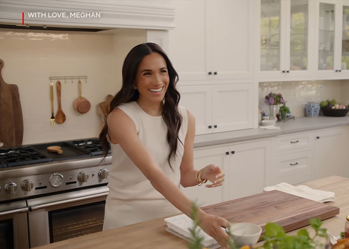 Meghan Markle smiling in a bright kitchen during her Harper’s Bazaar moment sparking viral internet reactions.