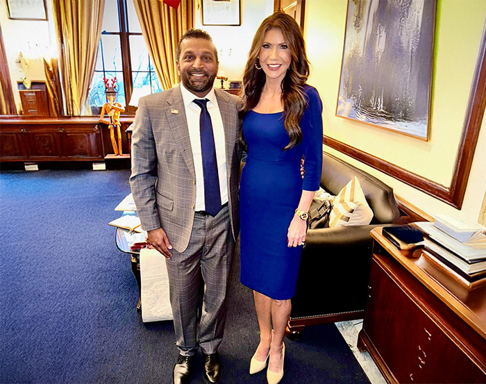 Kristi Noem standing in a blue dress beside a man in a suit in an office, showcasing her transformation over the years.