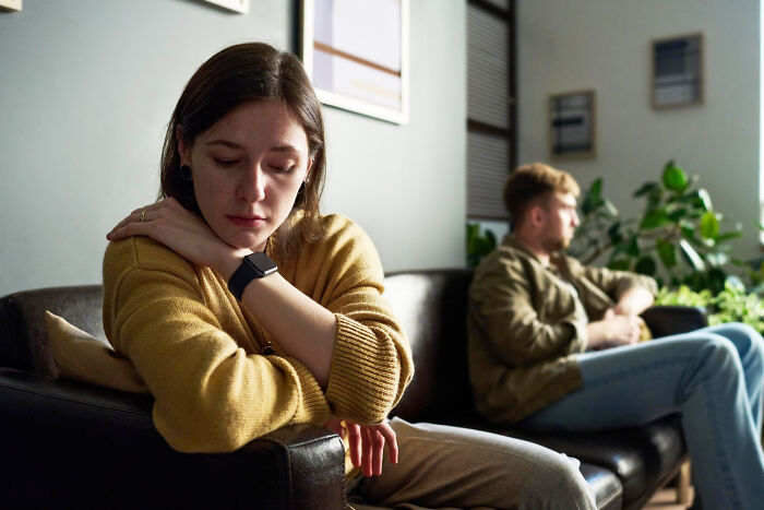 Sad woman sitting on couch avoiding man, illustrating people who messed up once and learned their lesson.